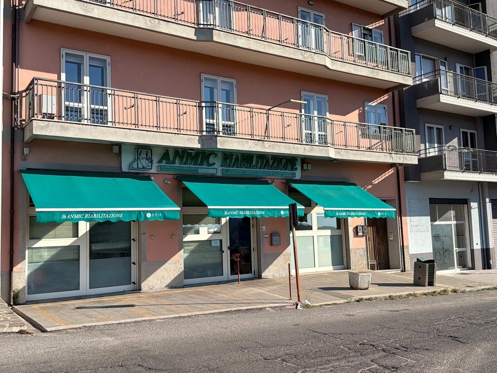 Ingresso della sede di San Giovanni in Fiore: vetrine con tende verdi e insegna ANMIC Riabilitazione