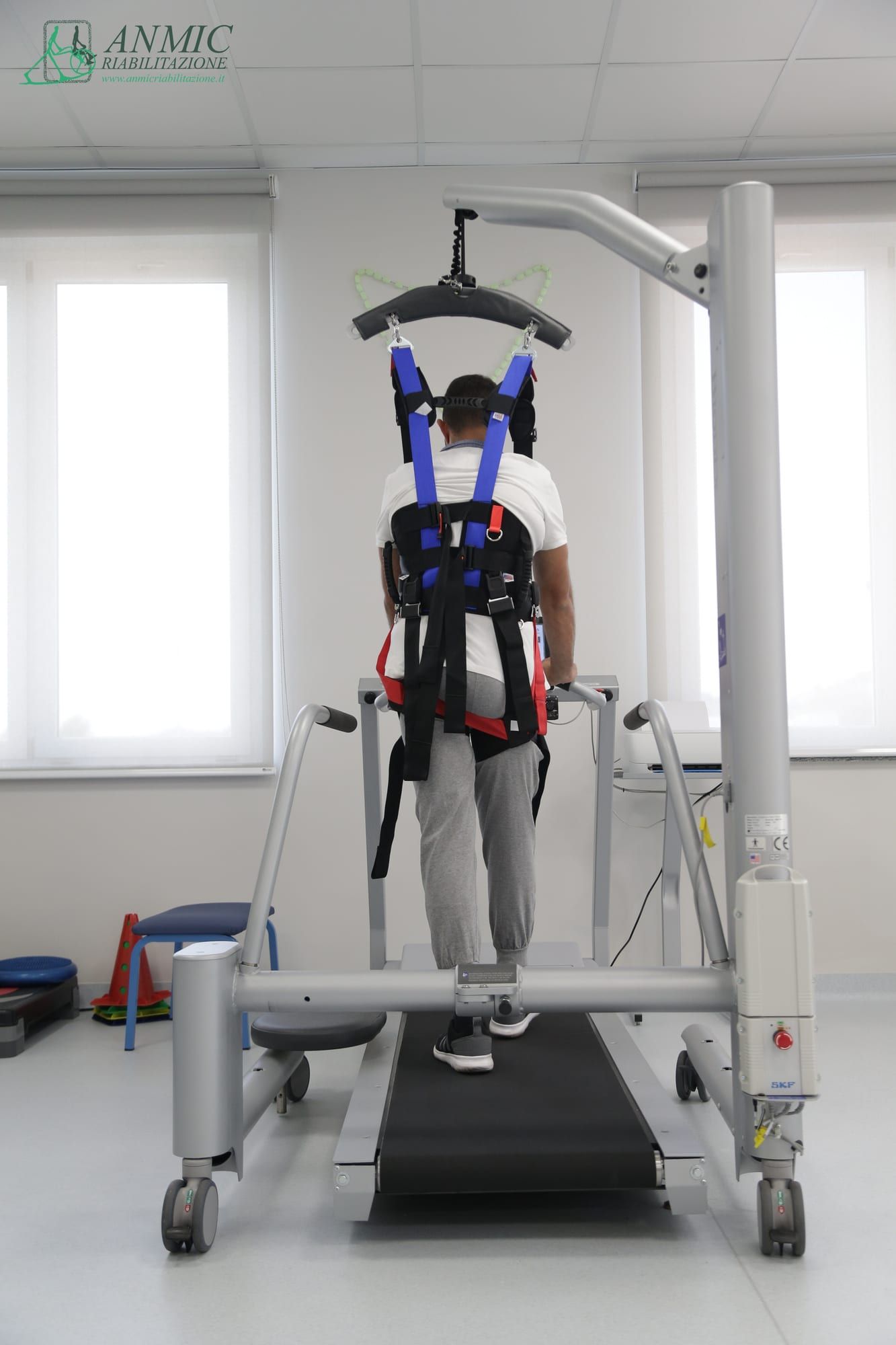 Paziente su treadmill con imbracatura durante una seduta di riabilitazione robotica
